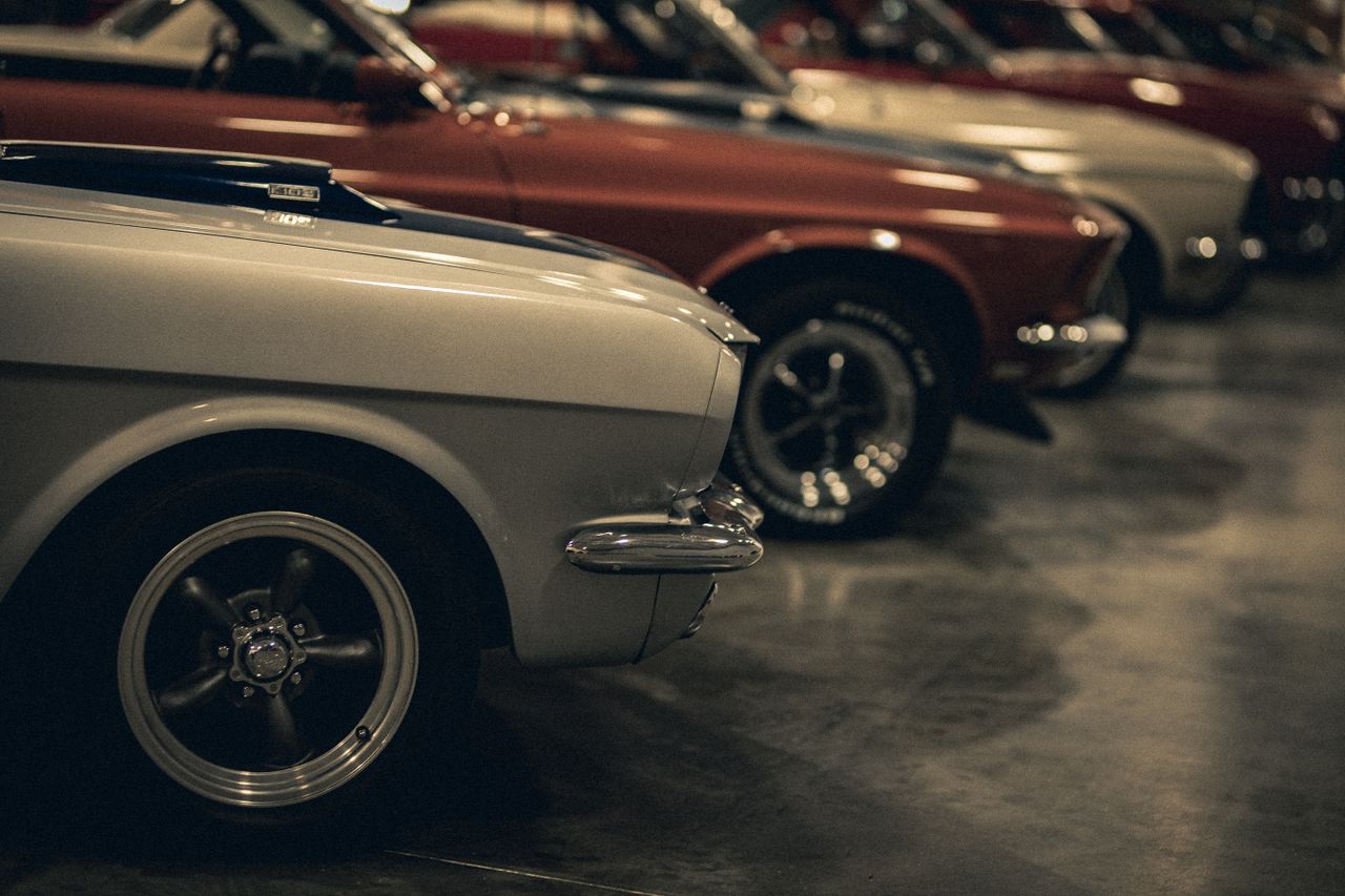 A close-up view of a row of classic vintage cars in a dimly lit garage showcasing elegance and retro design.